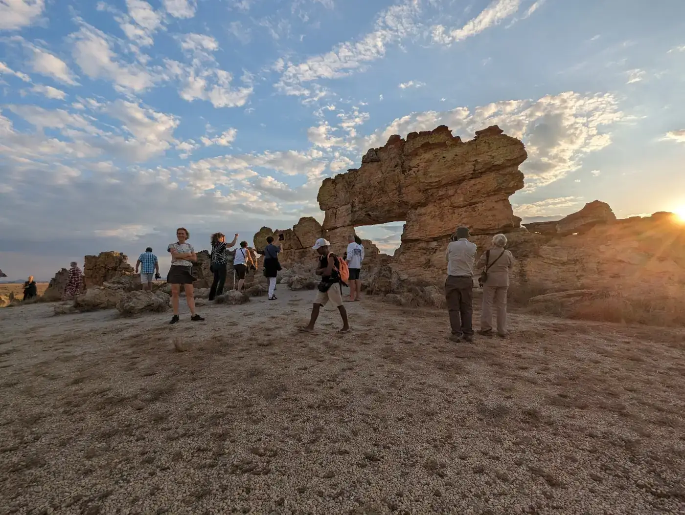 Group of travellers at a natural rock window at sunset